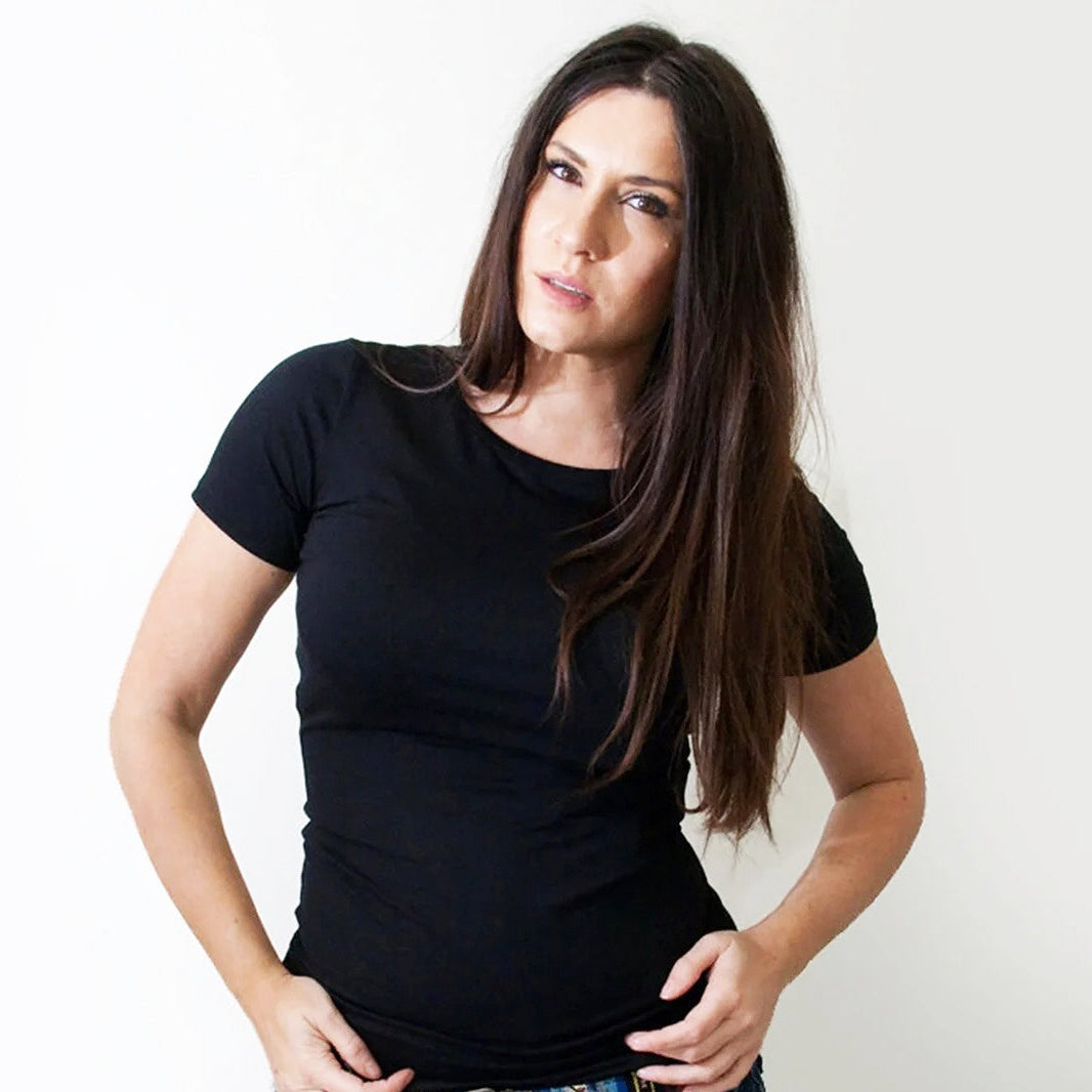 A woman with long dark brown hair wearing a plain black short-sleeve crewneck t-shirt, posing against a solid white background.